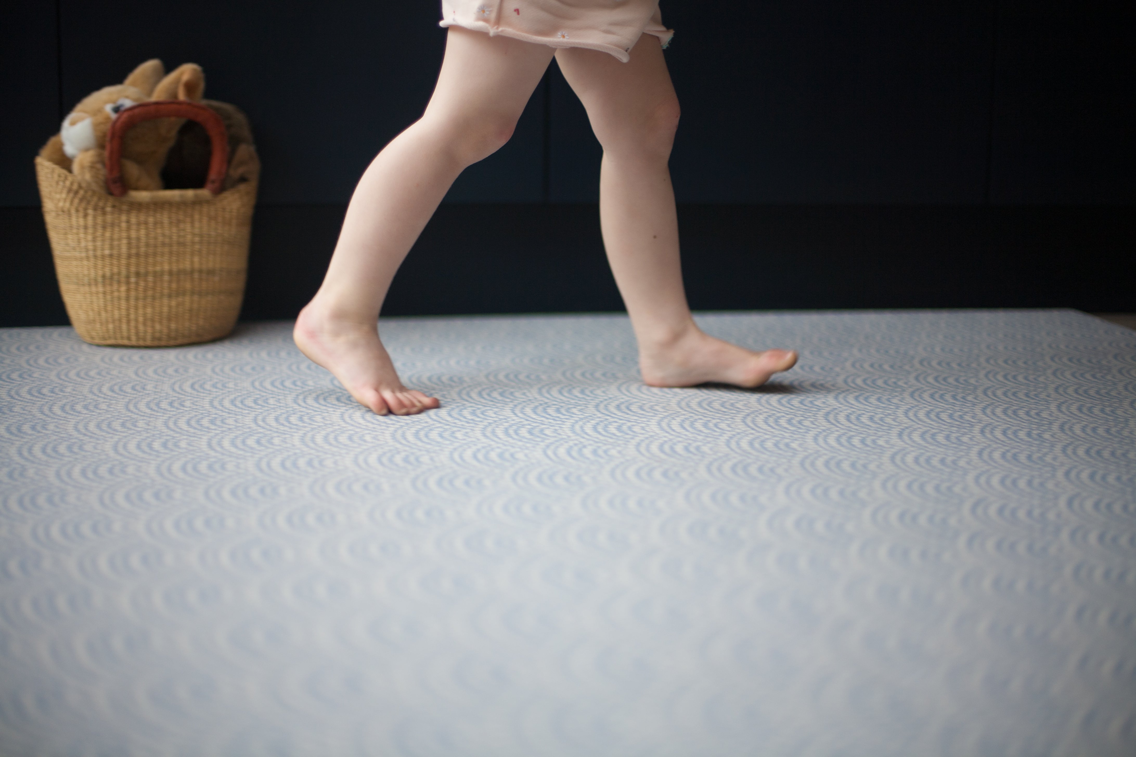 Toddler walking across Totter + Tumble's Seafarer iron blue playmat subtle pattern to fit in with your home interior