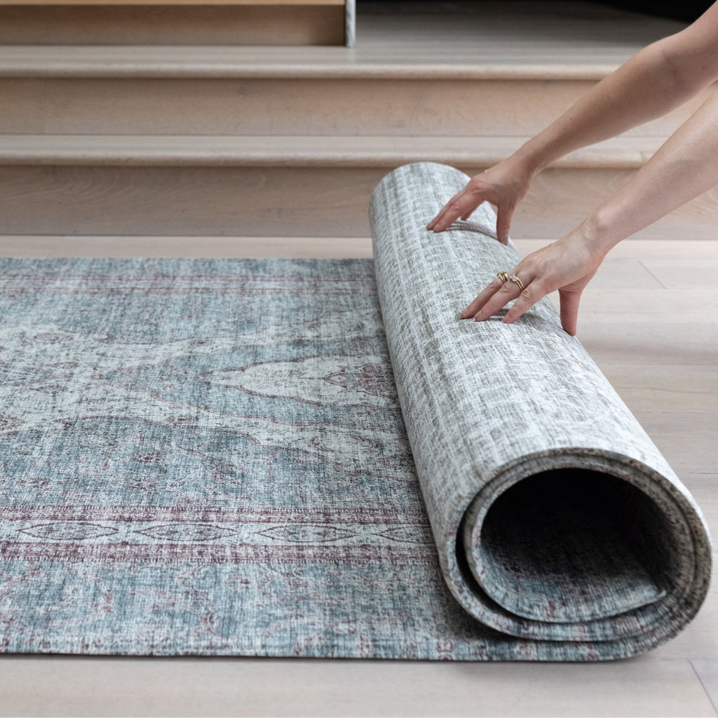 A rolled up playmat in extra large size. Showing a Persian rug design on one side and a timeworn textile style on the reverse.