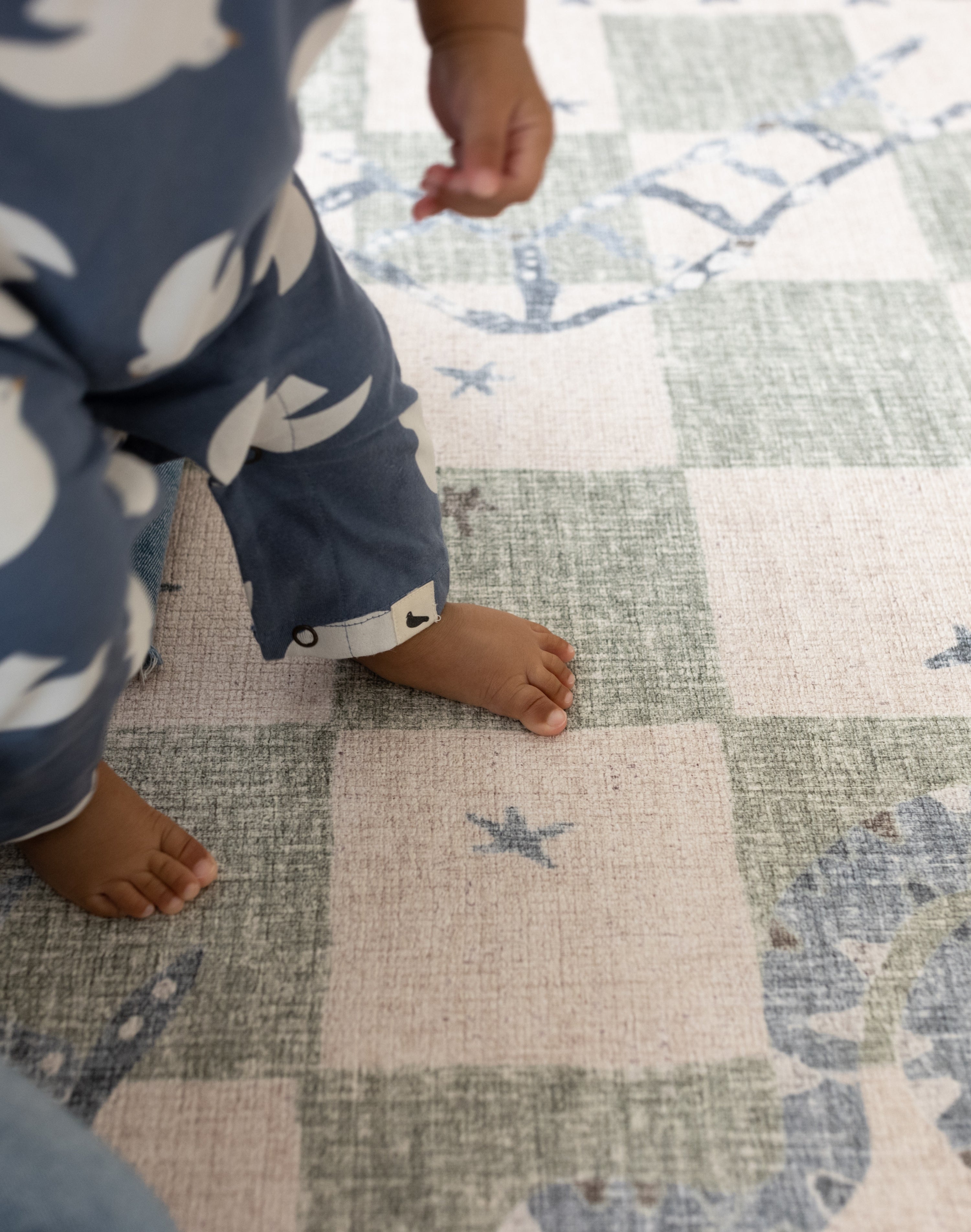 extra large baby play mat in snakes and ladders print with little toddler practising walking first steps supportive floor mat for babies learning key milestones