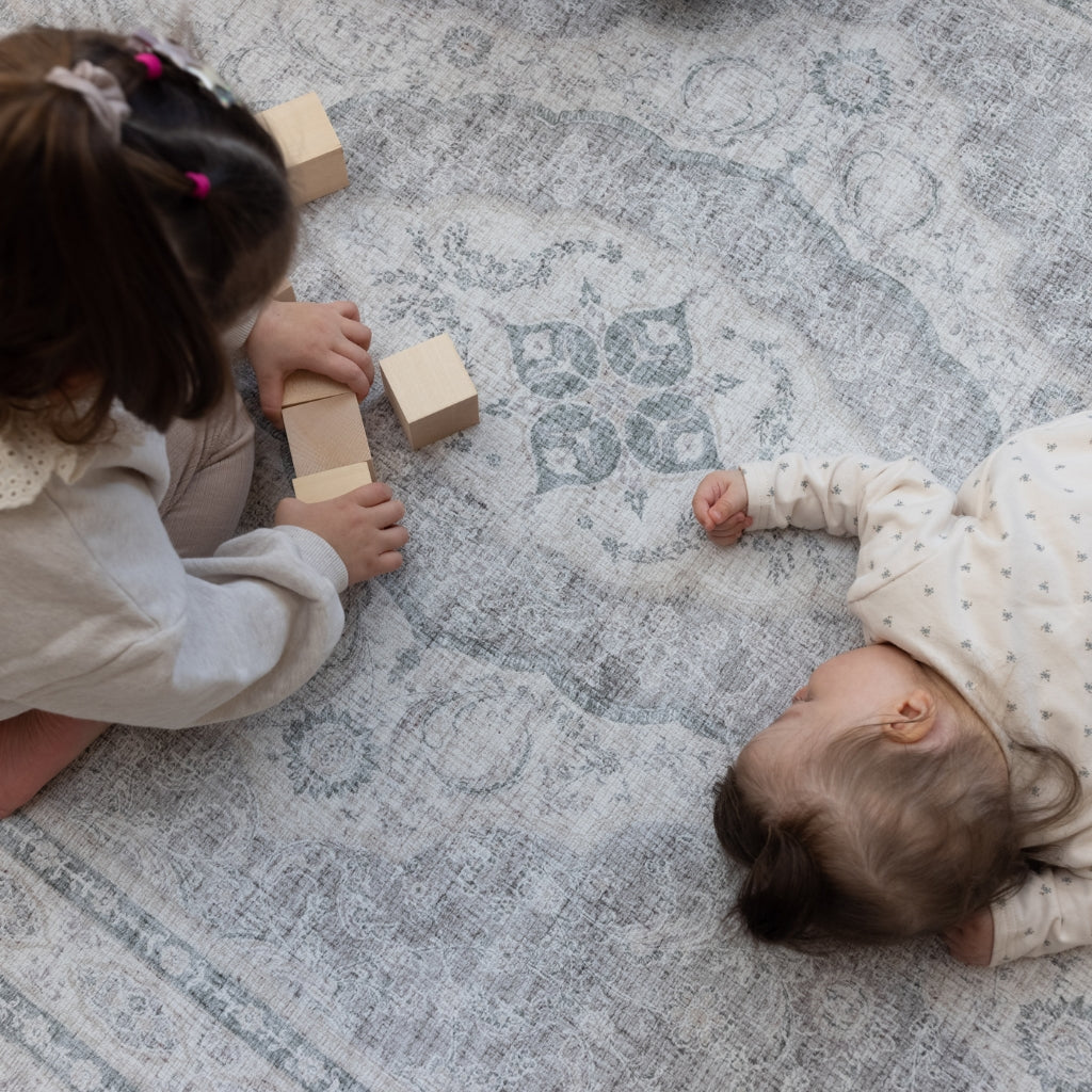 Two children play on an extra large grey Persian rug-style playmat