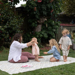 Woman and children playing outdoors on a totter and tumble playmat suitable for both indoors and outdoor use