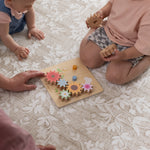 Two children playing with a wooden toy on a floral double sided totter and tumble design