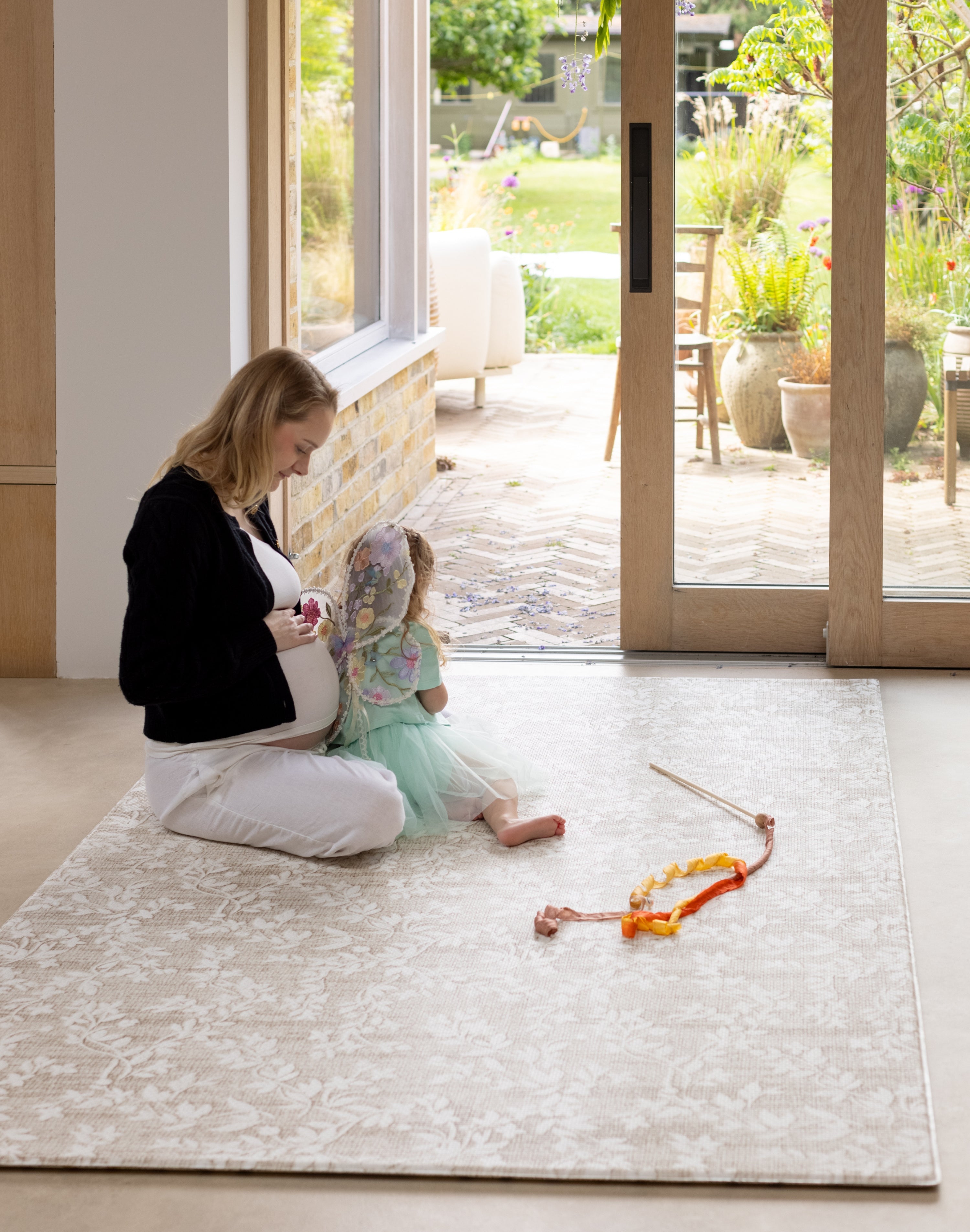 pregnant mother and child sitting on the totter and tumble playmat 