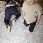 Toddlers sharing padded playmat in floral beige design in kids bedroom 
