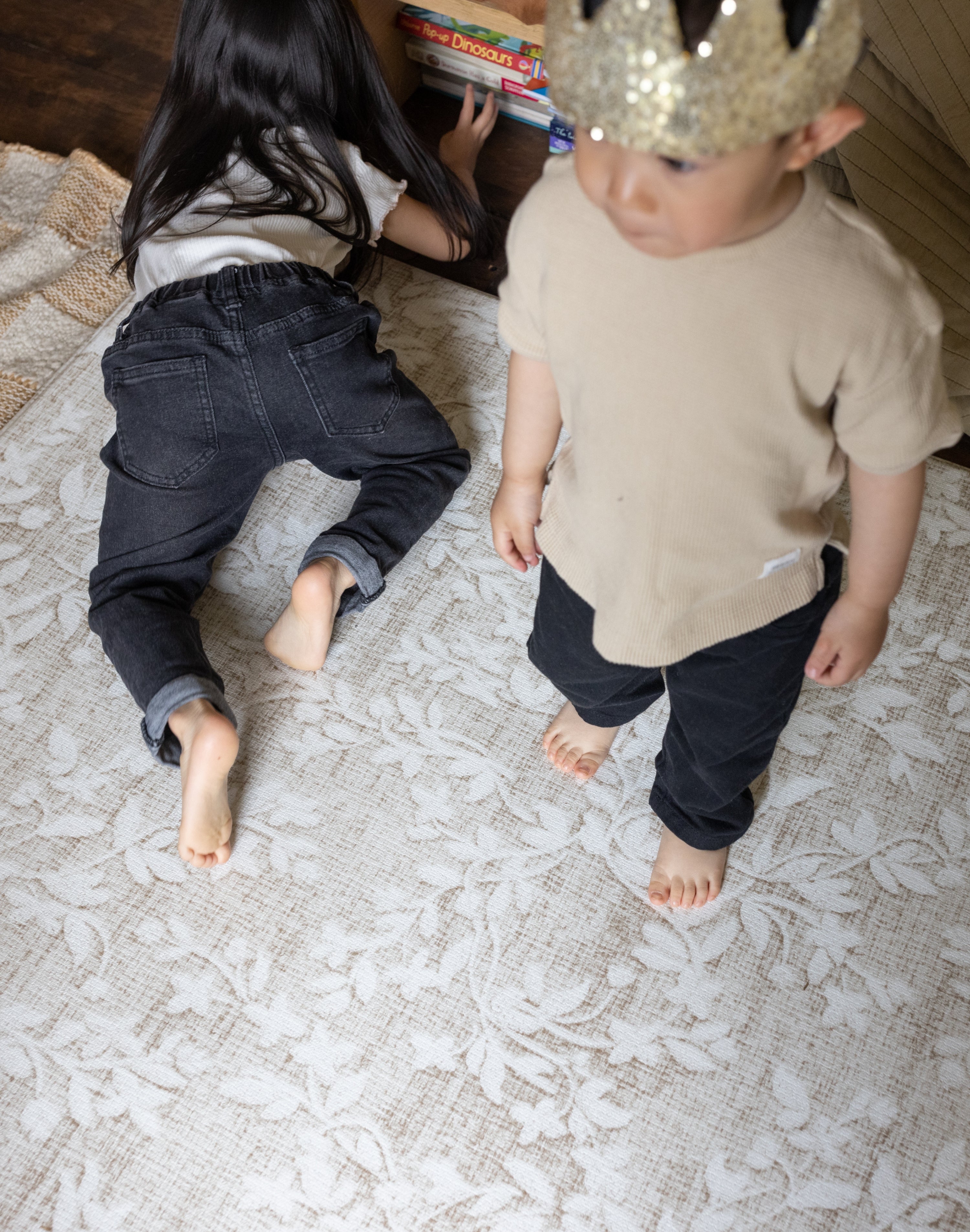 Toddlers sharing padded playmat in floral beige design in kids bedroom 