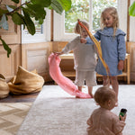 Three children playing with colorful ribbons in a home setting on the extra large totter and tumble one piece playmat
