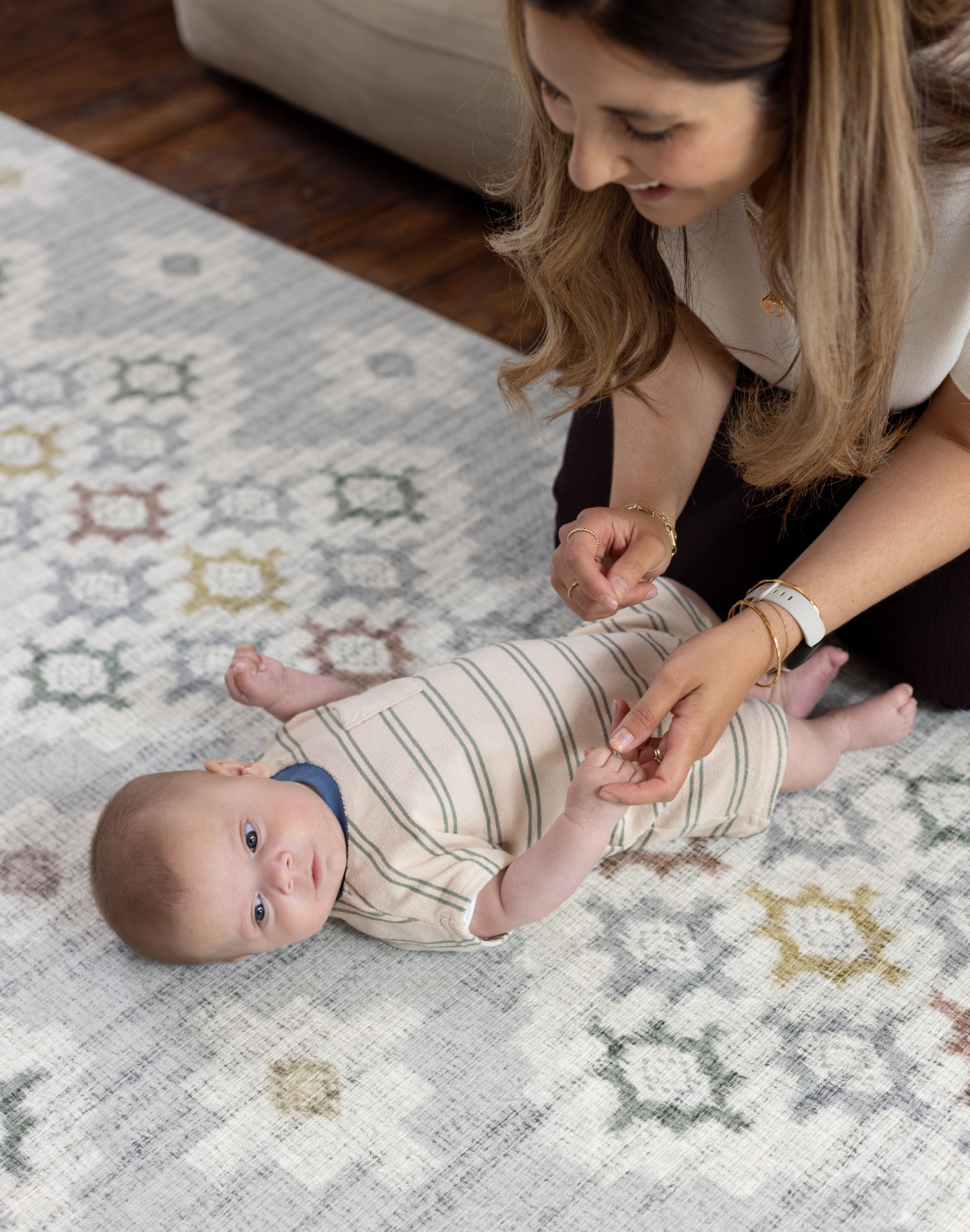 Woman playing with a  newborn baby on a Totter + Tumble playmat perfect maternity or welcome to the world gift baby shower