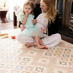 Mother and daughter sitting on floor in living room on Totter + tumble playmat