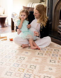 Mother and daughter sitting on floor in living room on Totter + tumble playmat