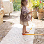 Little girl playing with a wand on a totter and tumble play runner suitable to use outside or indoors