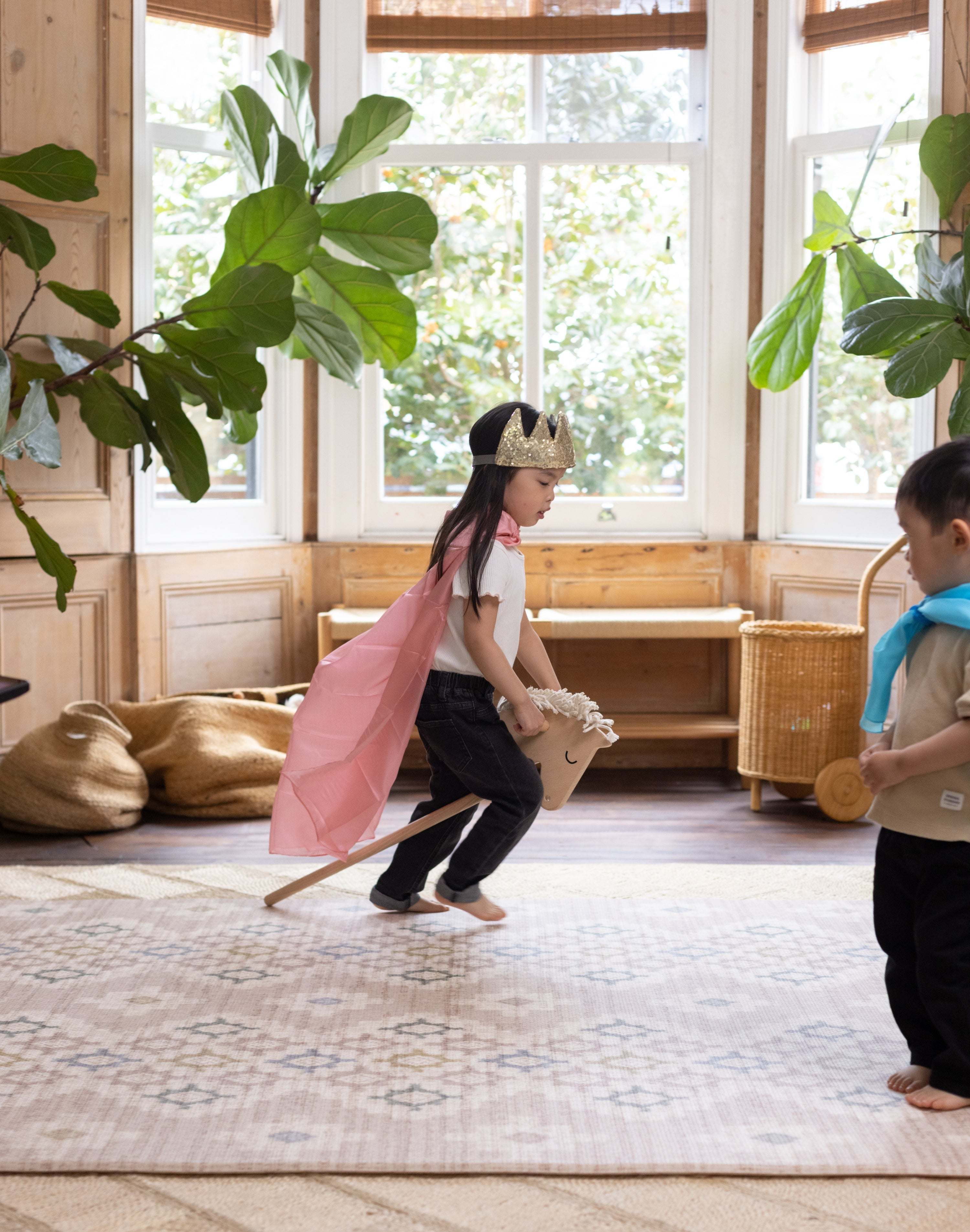 little girl playing with a hobby horse on playmat with crown magical childhood moments captured at home and on the floor with Totter + Tumble rug equivalent 