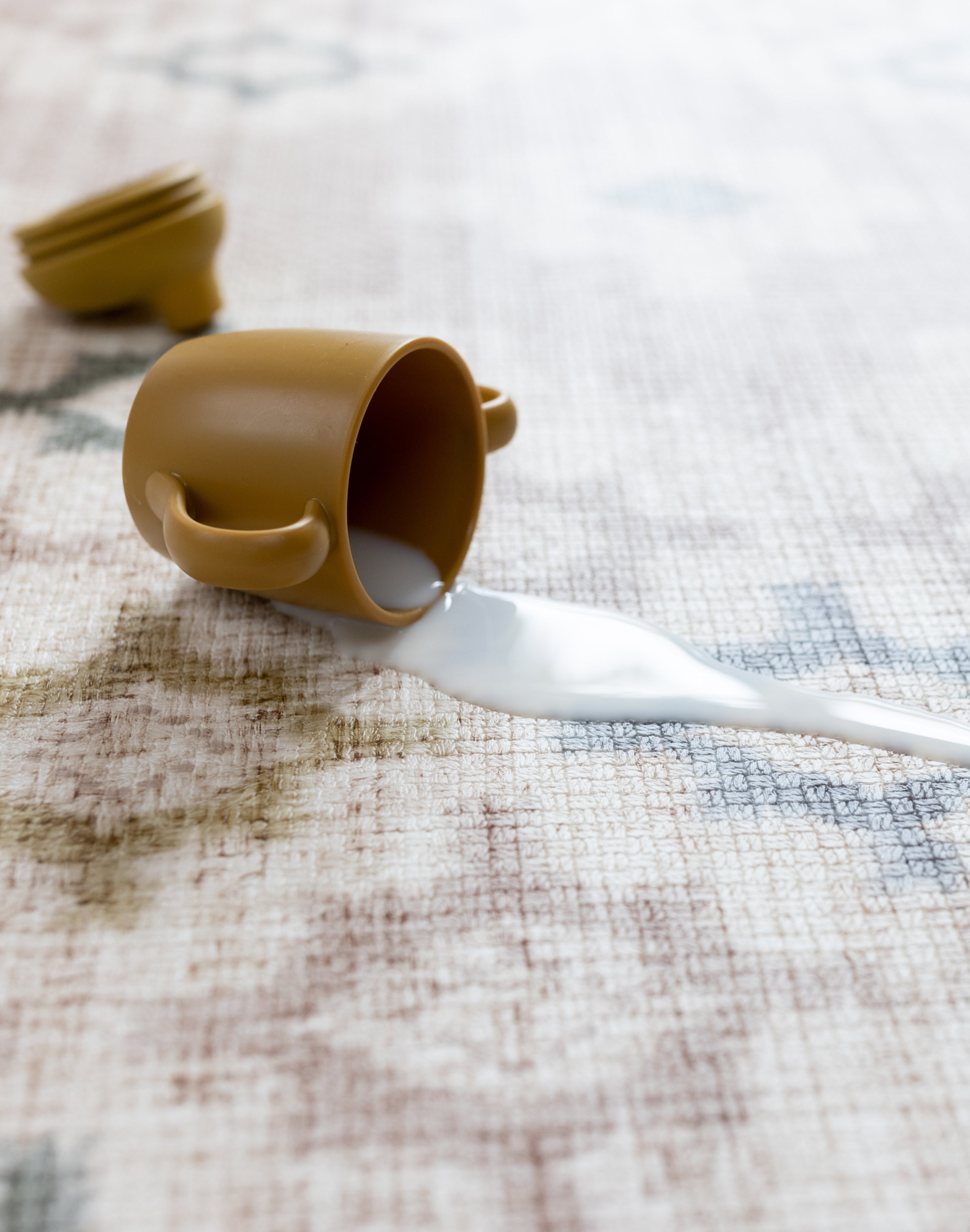 Brown cup with a white spill on a textured closed cell memory foam surface - antibacterial and easy to clean