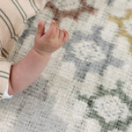 Close-up of a baby's hand on an area rug equivalent called totter and tumble play mat 