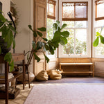 Living room with large windows, plants, and a wooden bench with a new for 2026 Aster pink floral design Totter and tumble playmat