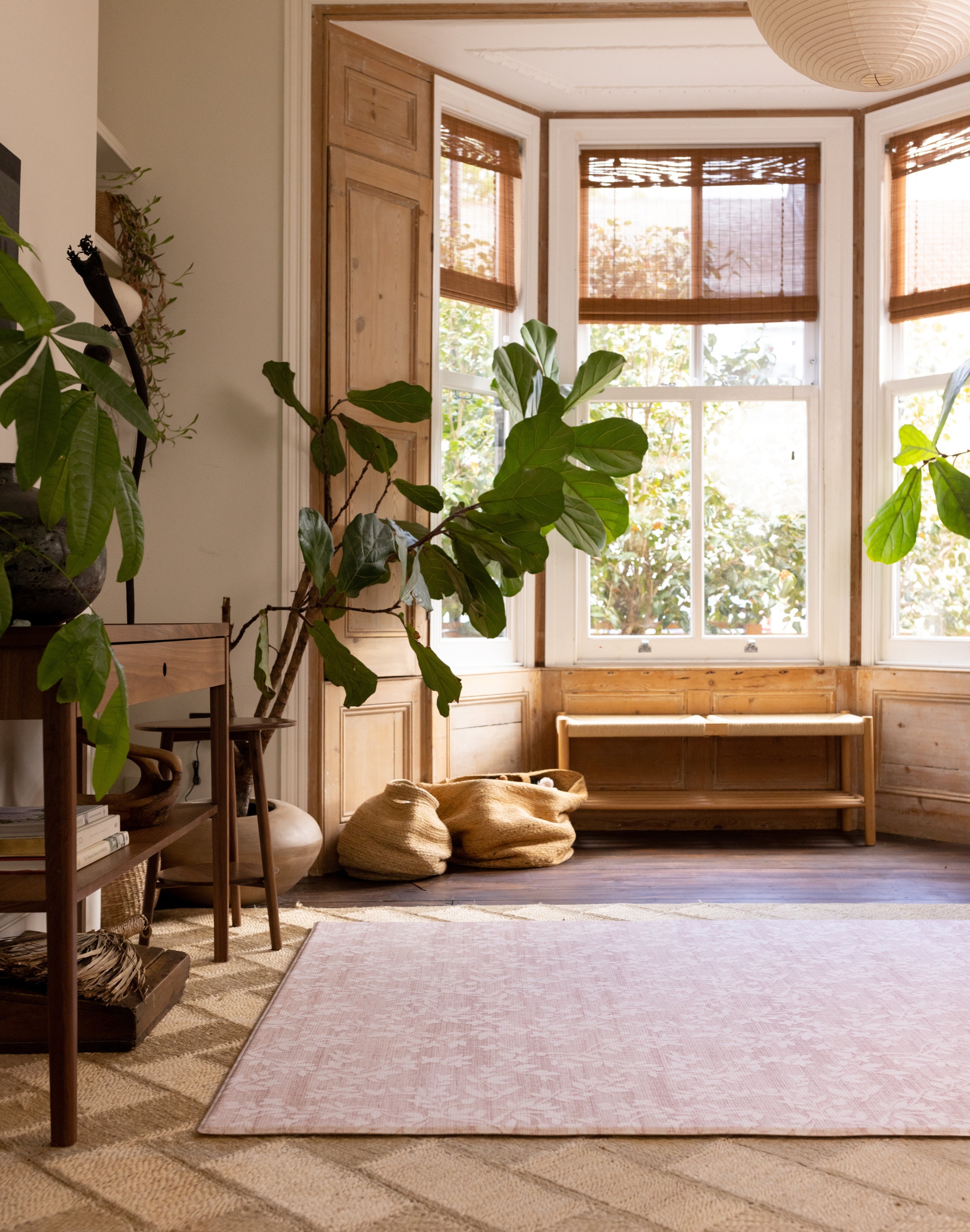 Living room with large windows, plants, and a wooden bench with a new for 2026 Aster pink floral design Totter and tumble playmat