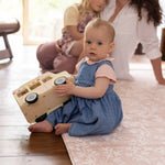 Little girl sitting on totter + tumble play mat playing with toys