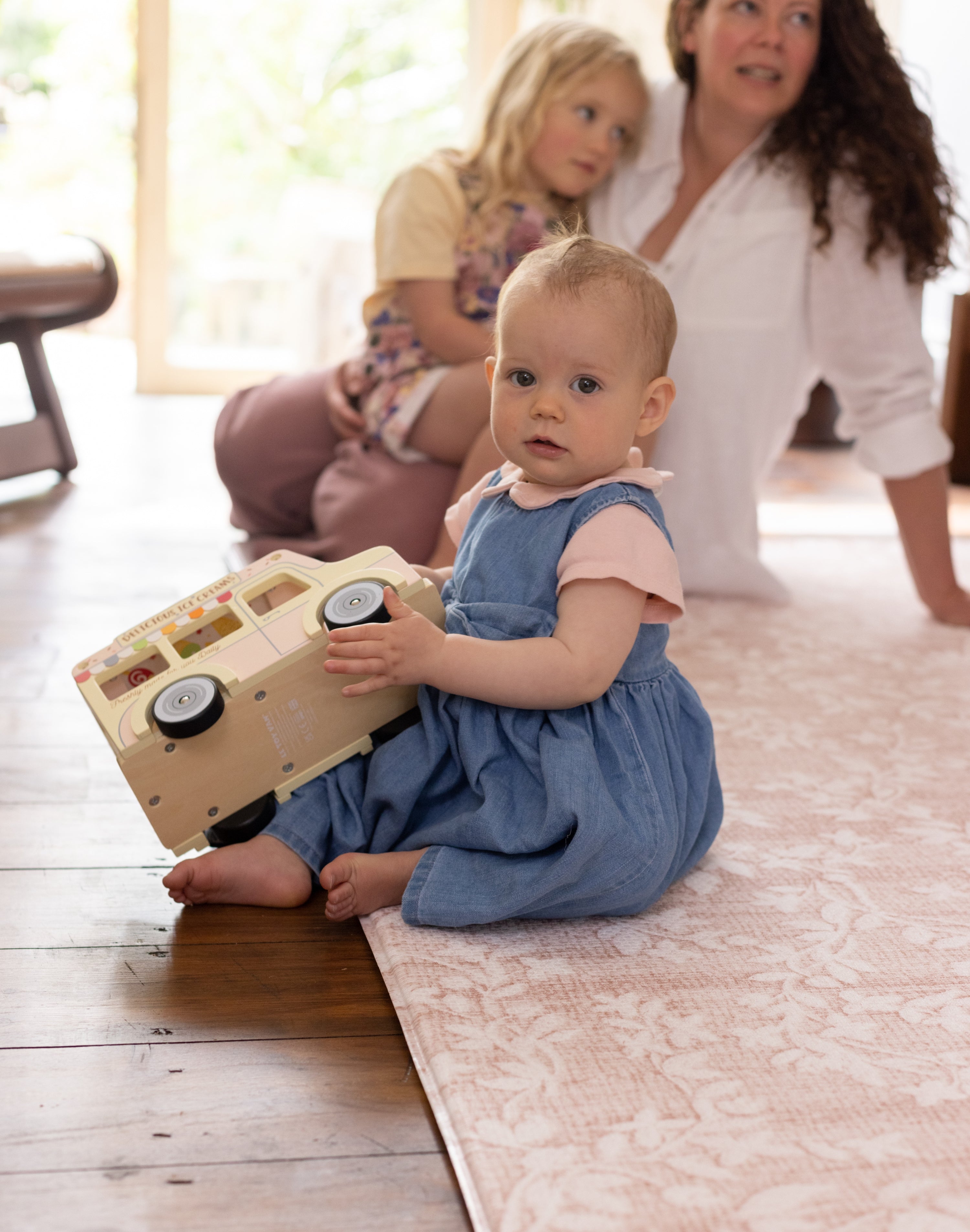 Little girl sitting on totter + tumble play mat playing with toys
