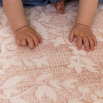 close up of babys hands resting and playing on pink playmat design perfect for nursery room 
