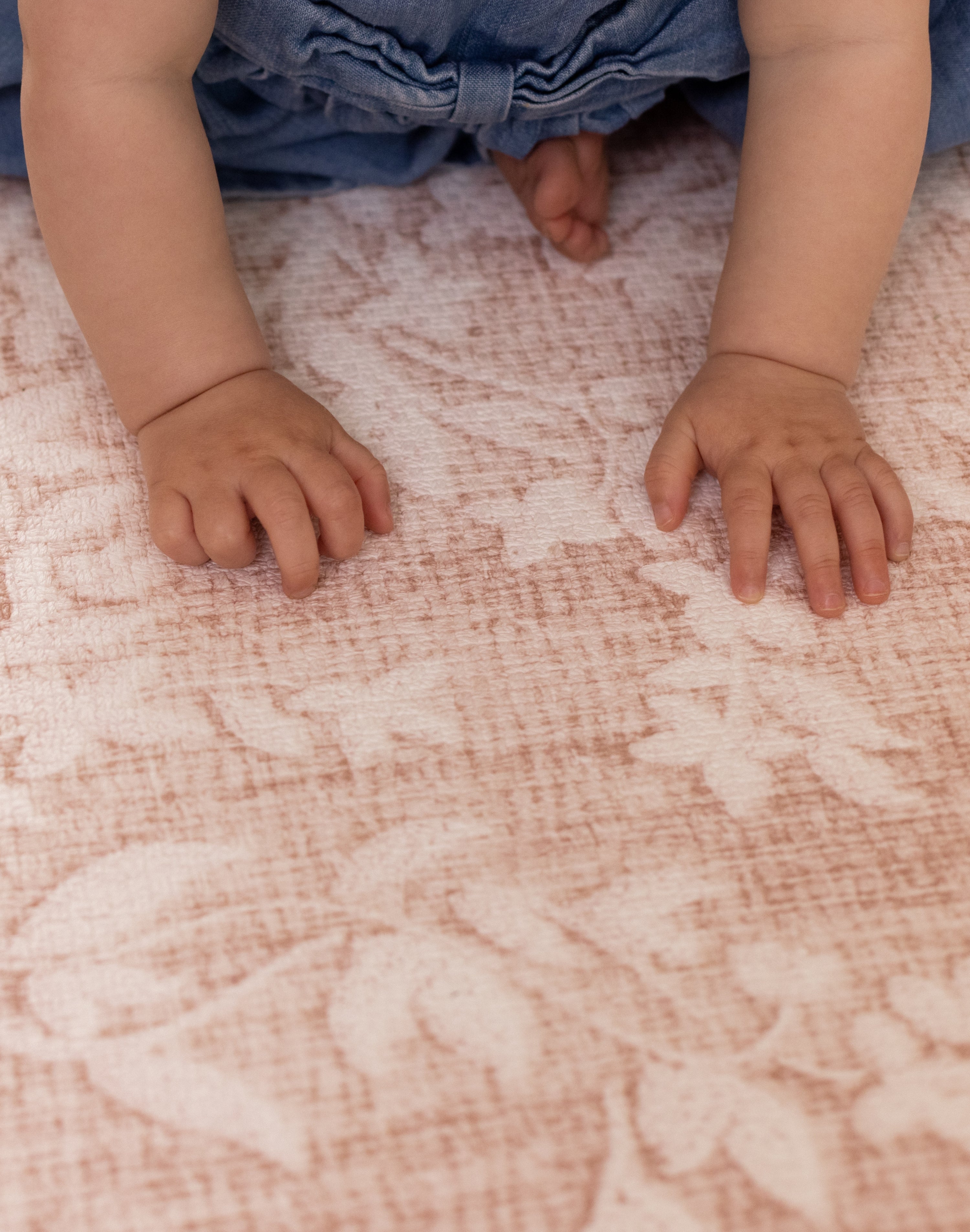 close up of babys hands resting and playing on pink playmat design perfect for nursery room 