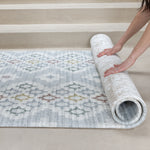 Person unrolling a patterned rug on a floor