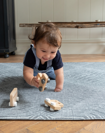 Baby boy crawls across the monochrome play mat Astronomer with a kilim design inspired by rugs 