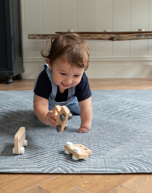 Baby boy crawls across the monochrome play mat Astronomer with a kilim design inspired by rugs 