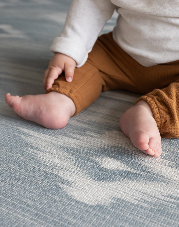 Close up of babies feet on Blue and beige baby play mat with stylish Ikat design ideal tumbling mat for babies and toddler for safe floor play thick memory foam adds comfort