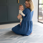 Mother holding baby on Large baby play mat in one piece to unroll in the home squishy memory foam surface to keep floor time comfortable and supported 