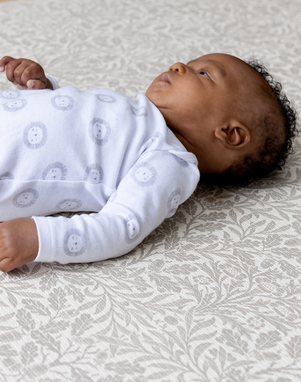 totter and tumble padded playmat in acorn morris & co print infant lying on playmat for floor