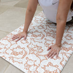 mother doing exercise stretches on totter and tumble runner playmat whilst baby sleeps