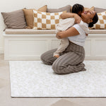 mother and toddler playing on neutral beige baby playmat