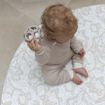 baby sitting on round neutral foam playmat with William Morris Bachelors Button design