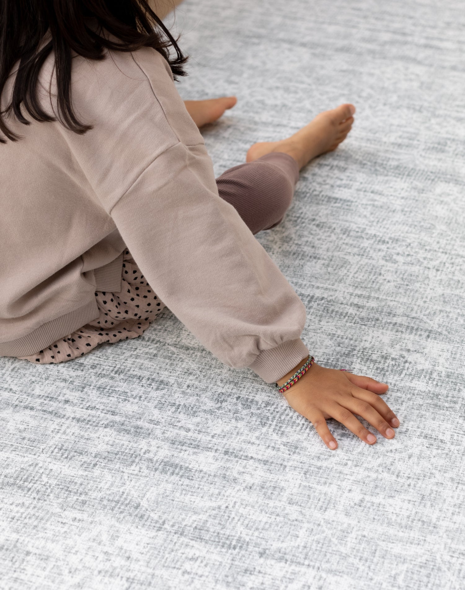 A child's hand touches a large cushioned play mat