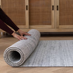 Hands roll out a large non slip mat that looks like a stylish rug