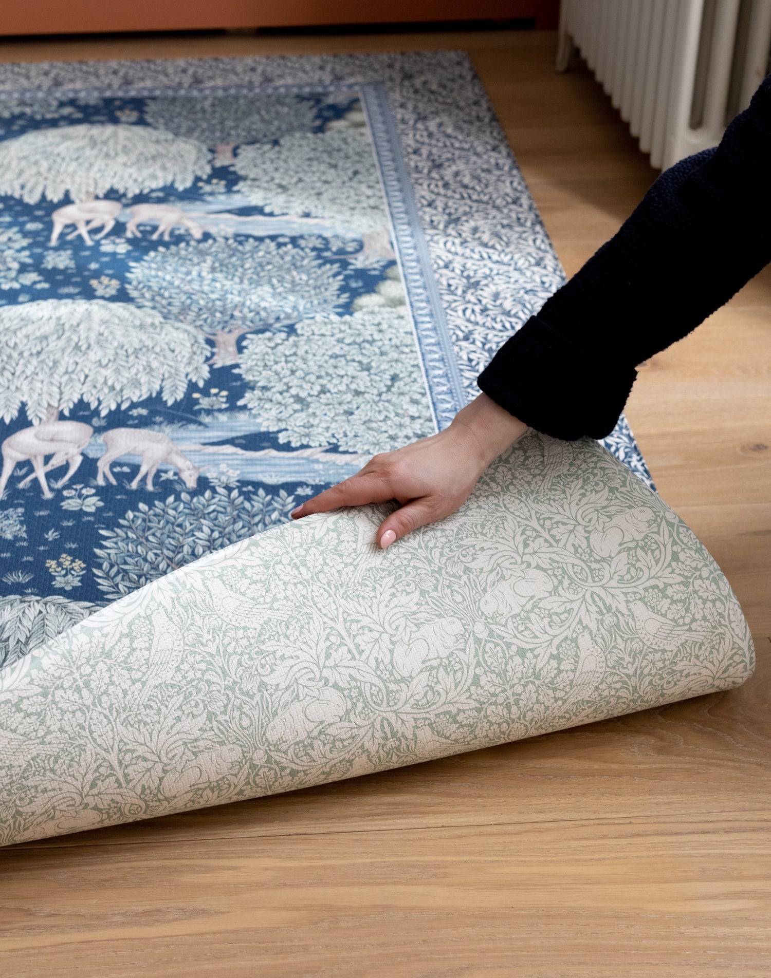 A large baby playmat is unrolled in a hallway, showing a double-sided floral design. A compact luxury playmat with rustic charm.