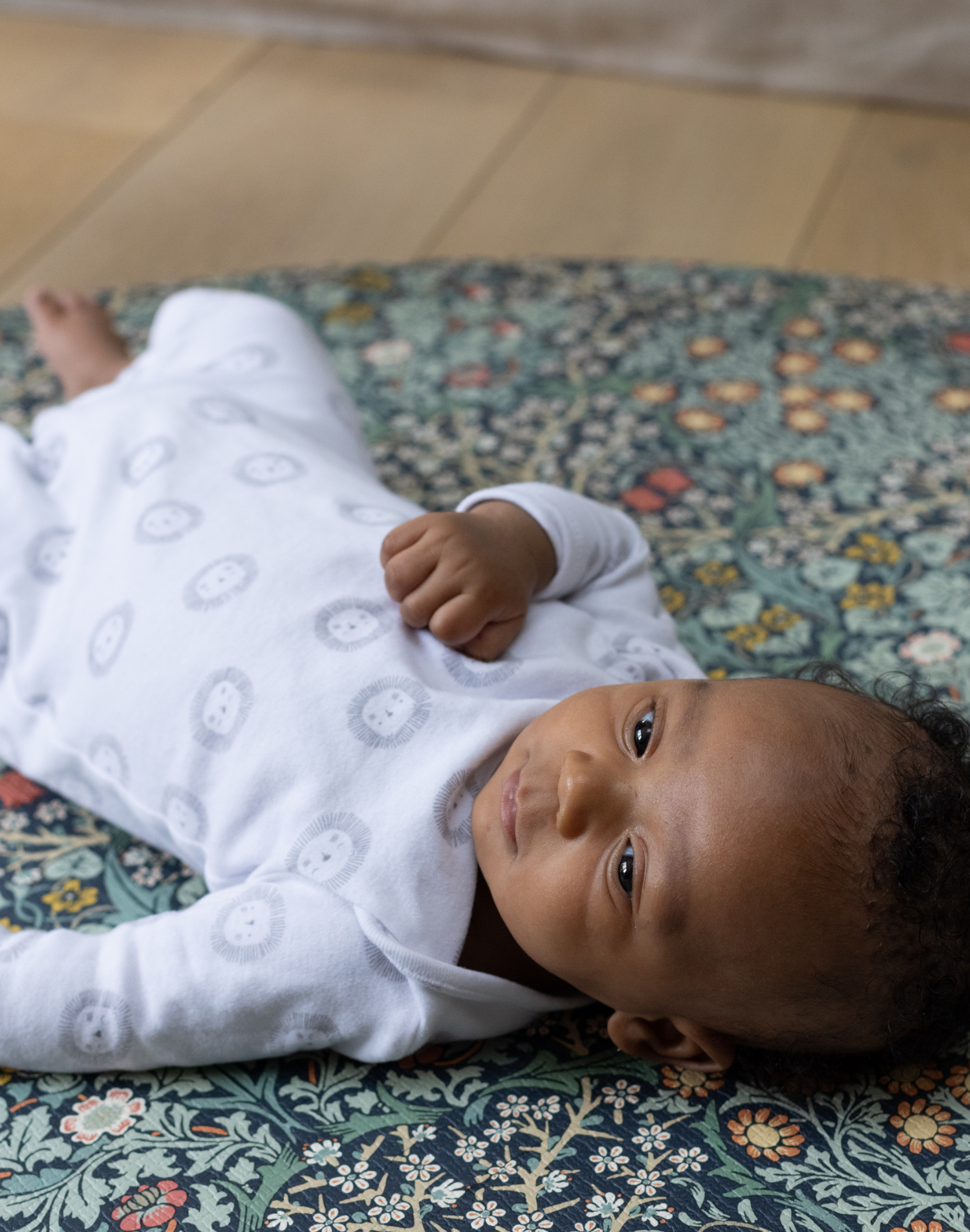 totter and tumble round size playmat in blackthorn morris& co print padded non toxic foam for kids baby lying on playmat happy child