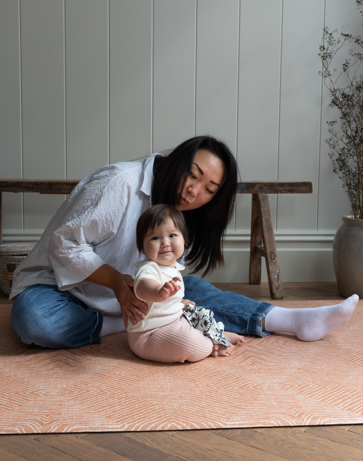 Mum and baby enjoy playing on the durable and safe playmat by totter and tumble with an earthy terracotta design