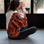 Mother holds baby sitting comfortably on the antibacterial playmat by totter and tumble 