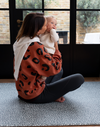 Mother holds baby sitting comfortably on the antibacterial playmat by totter and tumble 