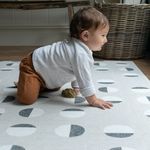 Toddler boy crawls across padded play mat that provides support during floor time and provides protection from the cold floor.