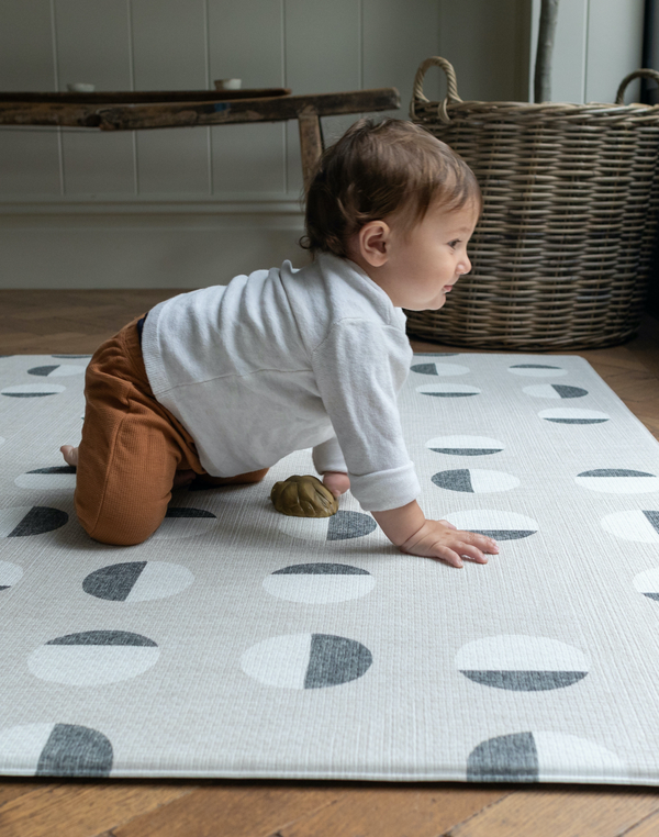 Toddler boy crawls across padded play mat that provides support during floor time and provides protection from the cold floor.