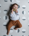 Baby chews on a teether and lays on textured baby play mat that provides support for all types of floor play 