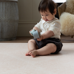 Little girl plays with stacking cups on comfortable soft playmat 