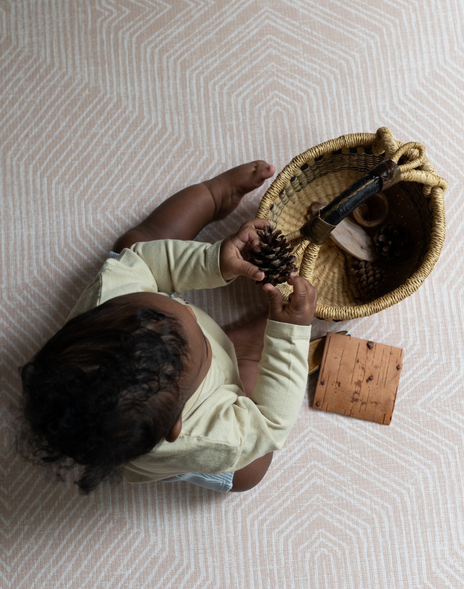 baby plays with natural sensory basket on the subtle, neutral pink soft Friend playmat from Totter and Tumble