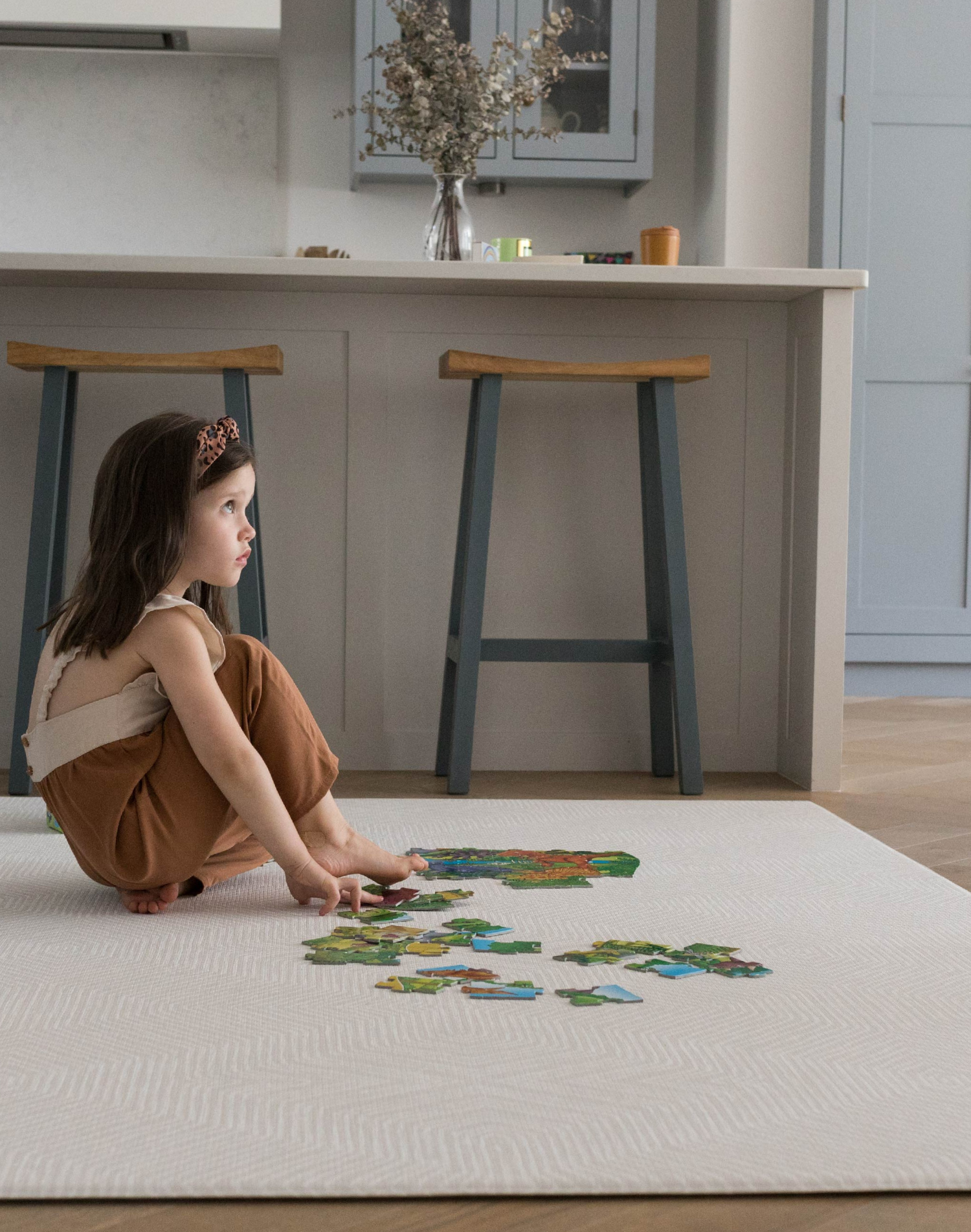 Little girl enjoys putting together a puzzle on the protective Globe Trotter floor mat that supports and cushions 