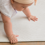 Baby crawls across thick padded play mat with stylish Kilim design that complements family homes