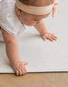 Baby crawls across thick padded play mat with stylish Kilim design that complements family homes