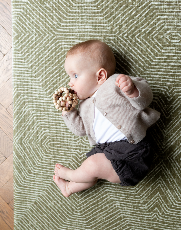 Baby rolls over on a textured baby mat that offers support for play time and development
