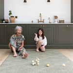 Grandmother and child sit on a large kitchen mat that has a modern kilim textile design to complement the interior 