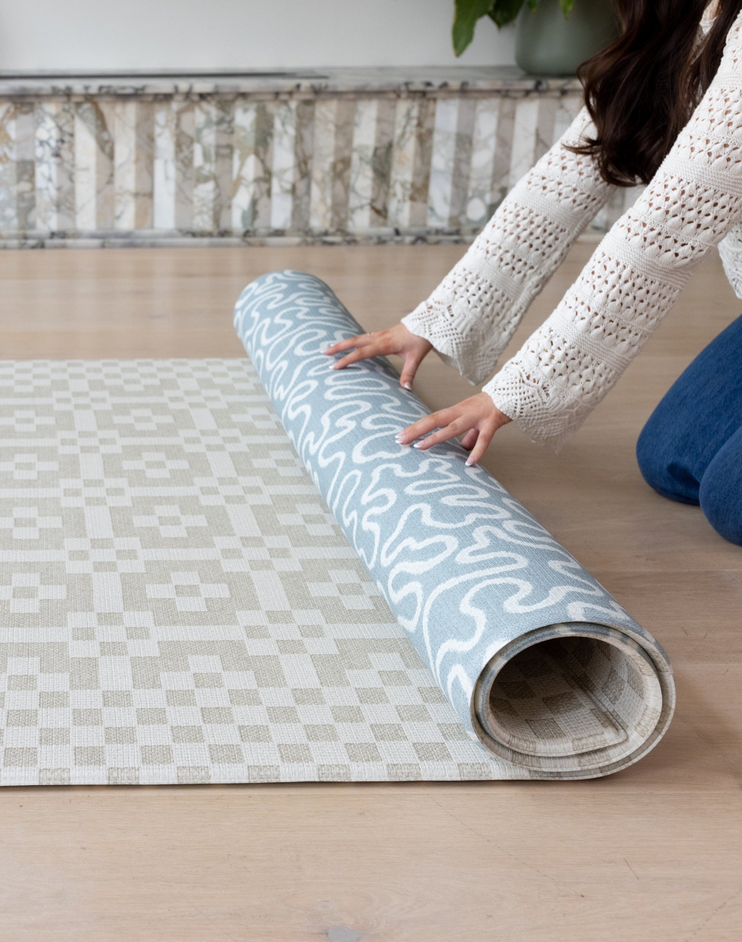 Rolling up The Pembroke, a compact, wipeable baby play mat with a coastal-inspired playmat pattern for modern homes.